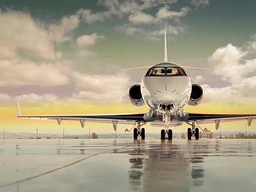 Private jet on the runway with reflection on wet surface and a colorful sky
